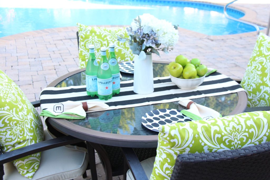 Pops of chartreuse green pillows and monogrammed dinner napkins complete this outdoor look. www.jennelyinteriors.com